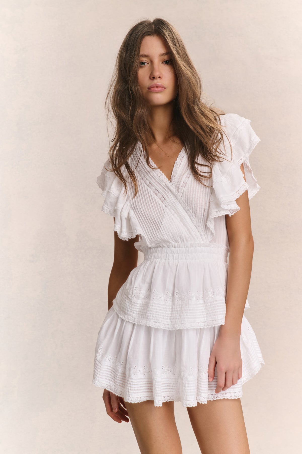White mini dress with V-neck and short ruffled sleeves, layered tiered skirt