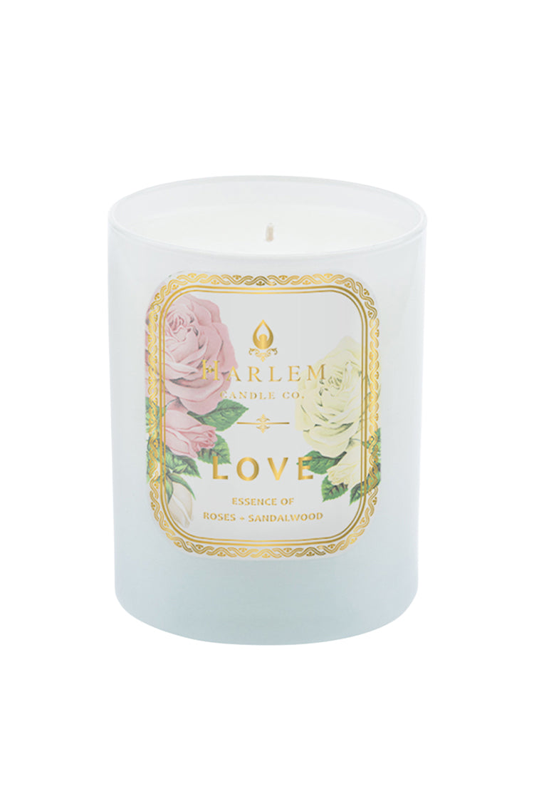 White pillar candle with floral βHarlemβ and βLoveβ label, small flame