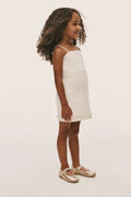 Ivory mini girls dress with spaghetti straps, straight skirt, eyelet-trim hem (side view)