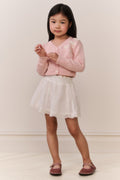Girls pink cardigan with bow embroidery, worn over a white lace skirt
