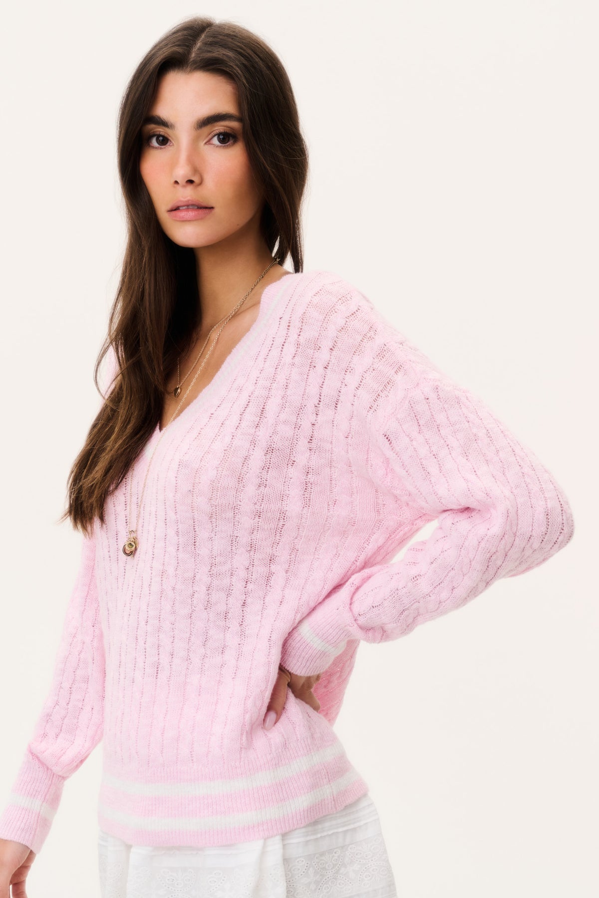 Pink cable knit pullover sweater with V-neck, long sleeves, and striped waist band