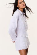 White eyelet button-up top with long sleeves and scalloped hem, front buttons.