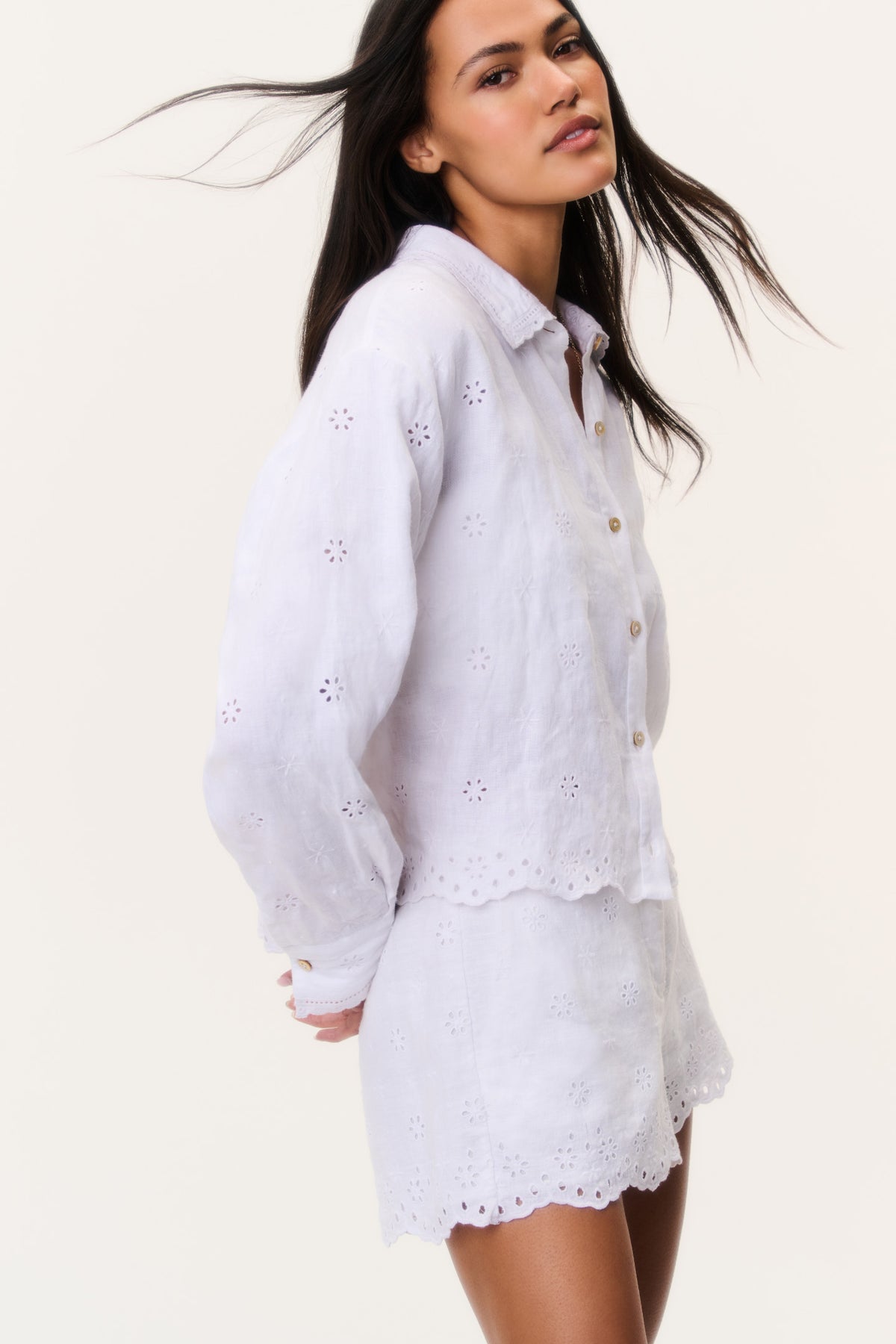 White eyelet button-up top with long sleeves and scalloped hem, front buttons.