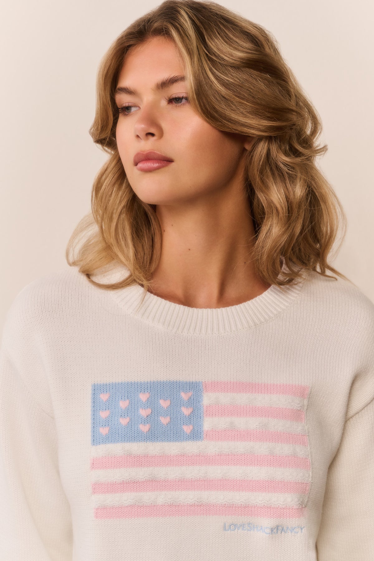Ivory knit flag pullover with close-up blue-and-pink striped flag graphic