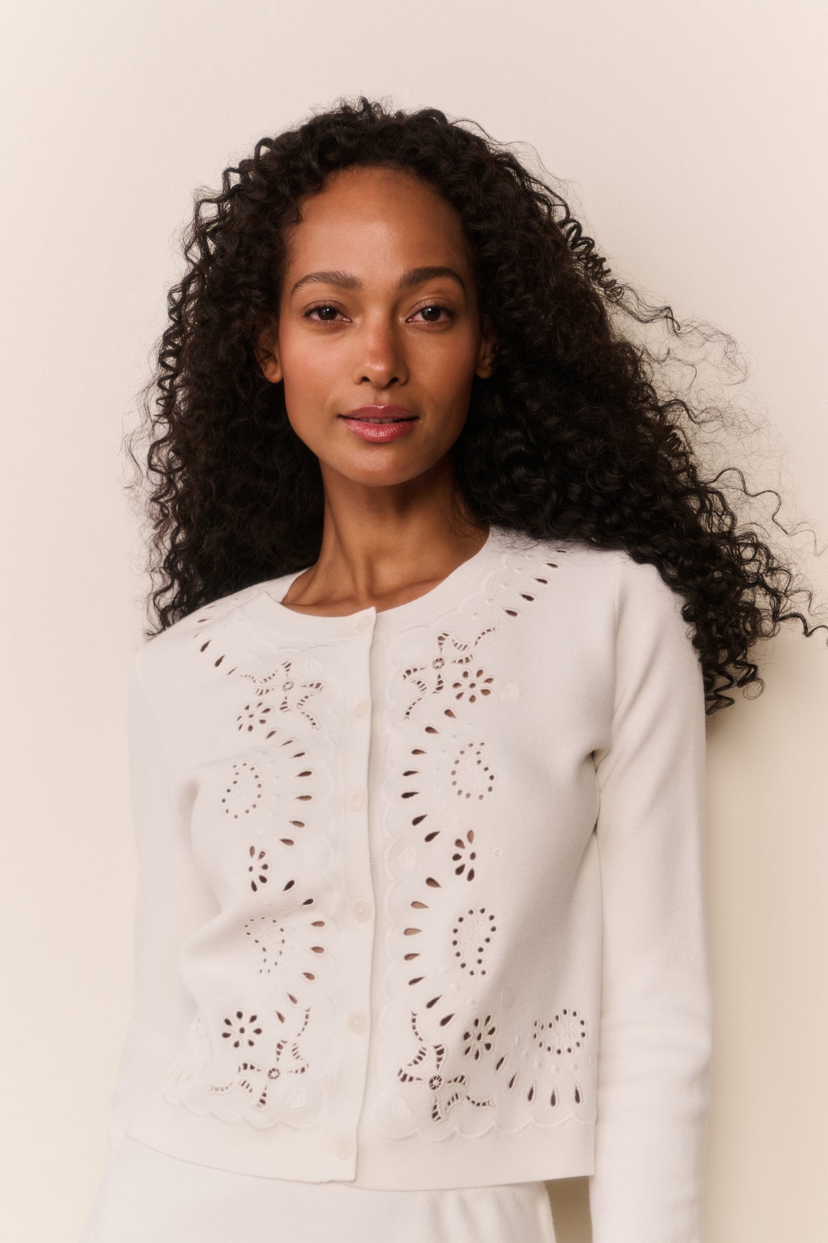 White eyelet knit cardigan close-up with button front and detailed embroidered eyelets.