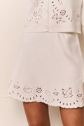 White knit mini skirt front with eyelet cutouts and scalloped hem detail