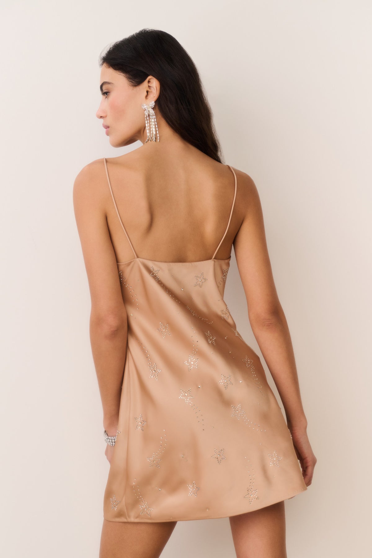 Gold satin mini dress with thin spaghetti straps and celestial crystal star print, back view
