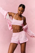 Pink gingham windbreaker shorts with elastic waistband and ruffled hem, styled on model