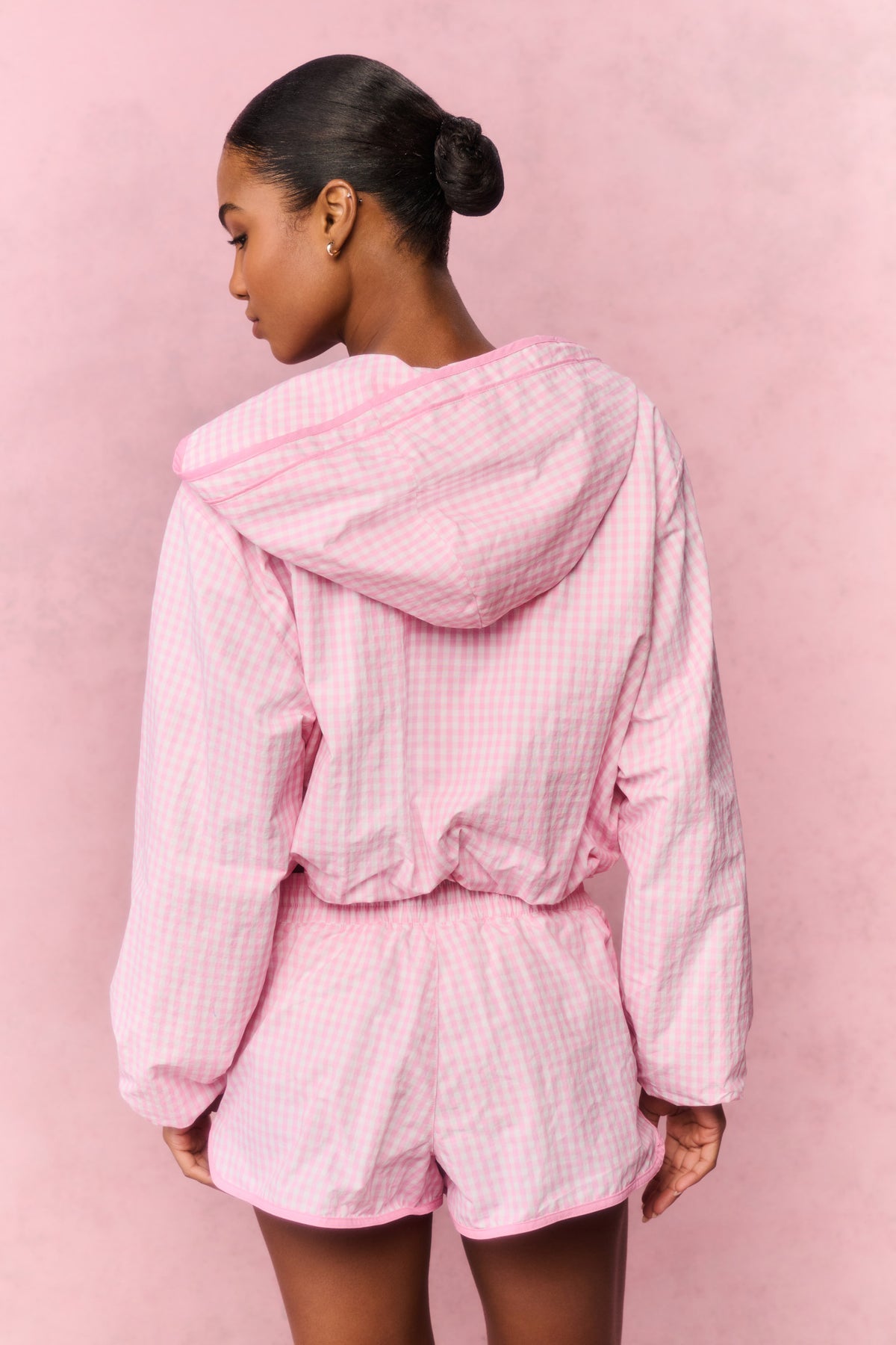 Pink gingham hooded windbreaker, view from back, gathered waist and long sleeves.