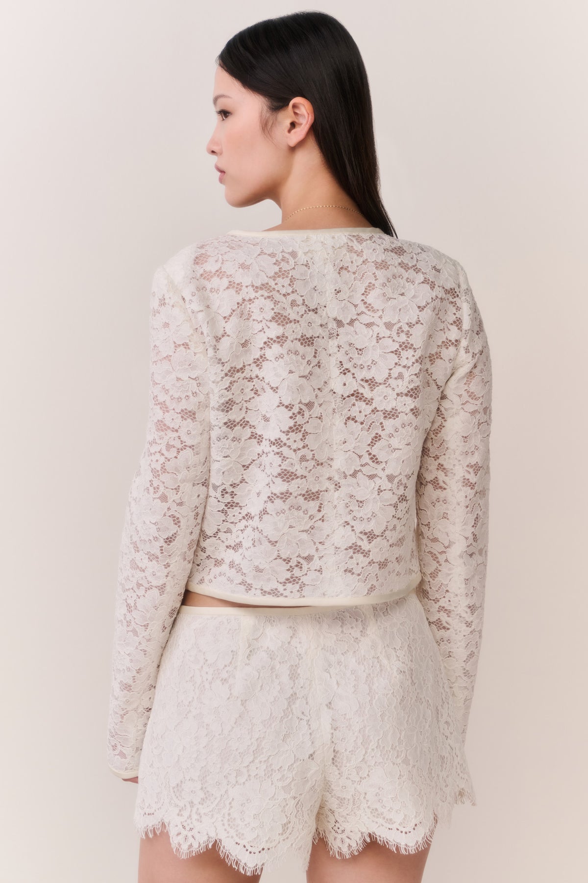 Ivory lace cropped jacket with long sleeves, scalloped hem, detailed back lace