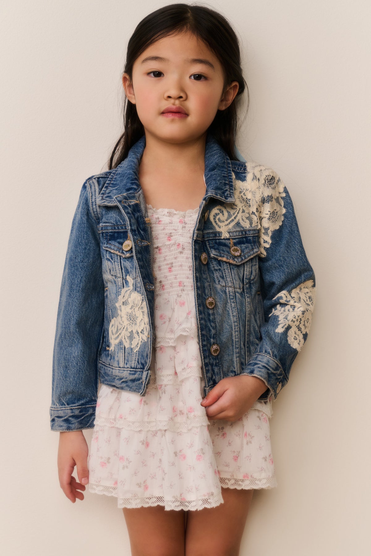 Girls' faded blue denim jacket with embroidered lace-style patches and chest pockets