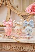 Pink floral fragrance tray display with decorative mini porcelain bottles and bows