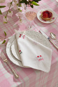 White embroidered napkin with red floral bow and scalloped lace edge