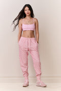 Pink printed cotton sweatpants on model, front view with elastic cuffs and tapered legs