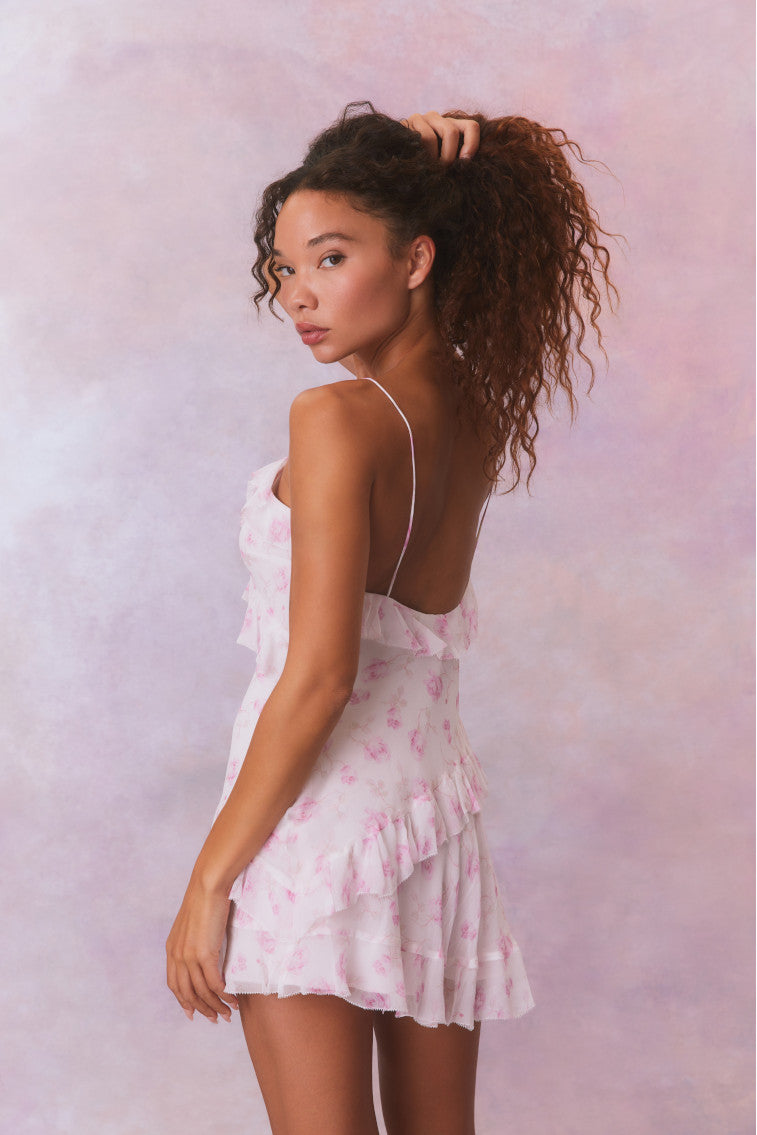 Silk mini dress with open back, thin spaghetti straps, and pink floral print ruffles.