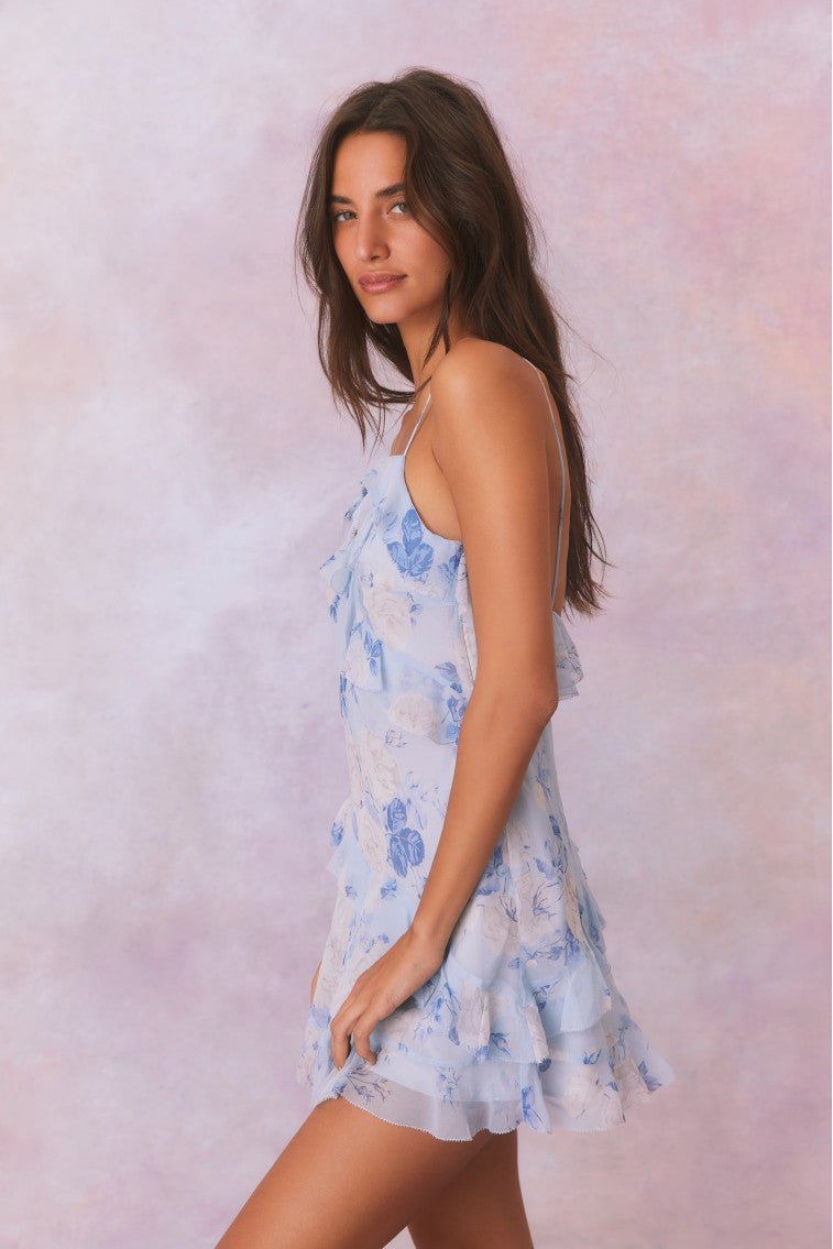 Silk mini dress with blue floral print and spaghetti straps, side view with ruffle hem.