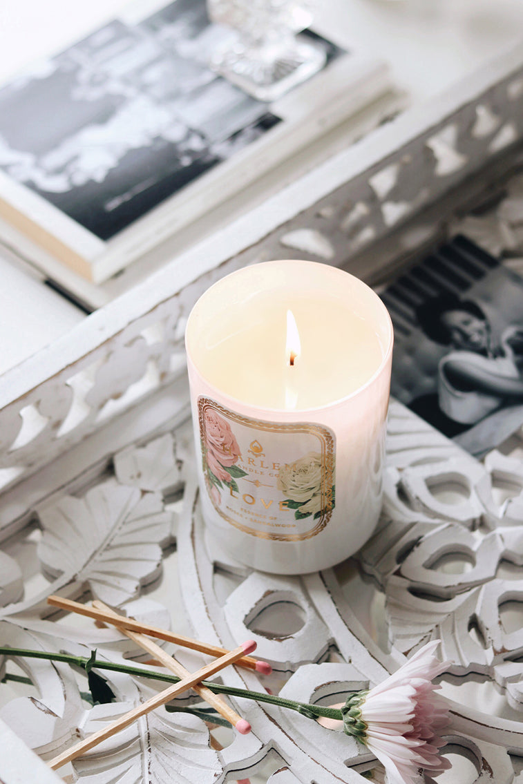White scented candle with flame on decorative paper and dried flowers
