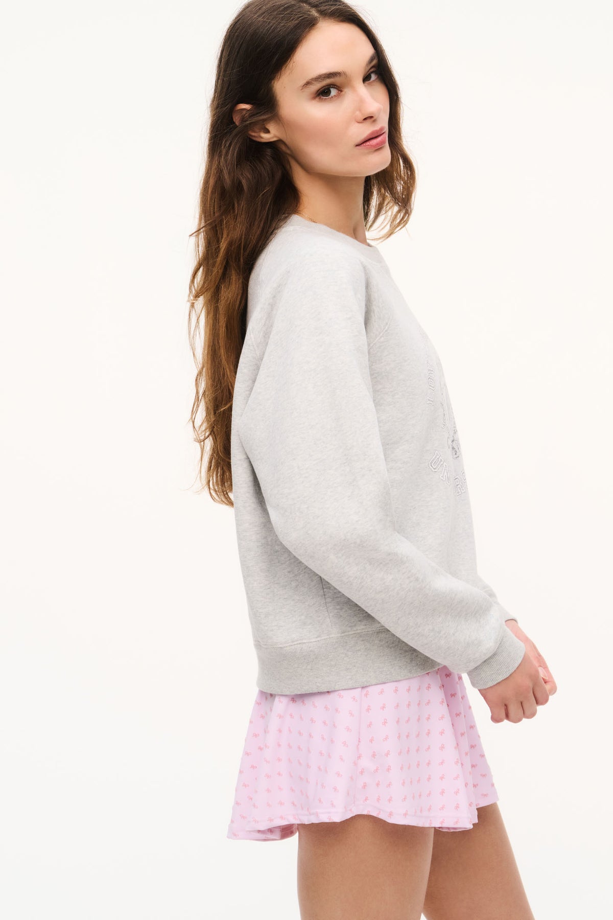 Light heather gray sweatshirt with crewneck and crest graphic, side view
