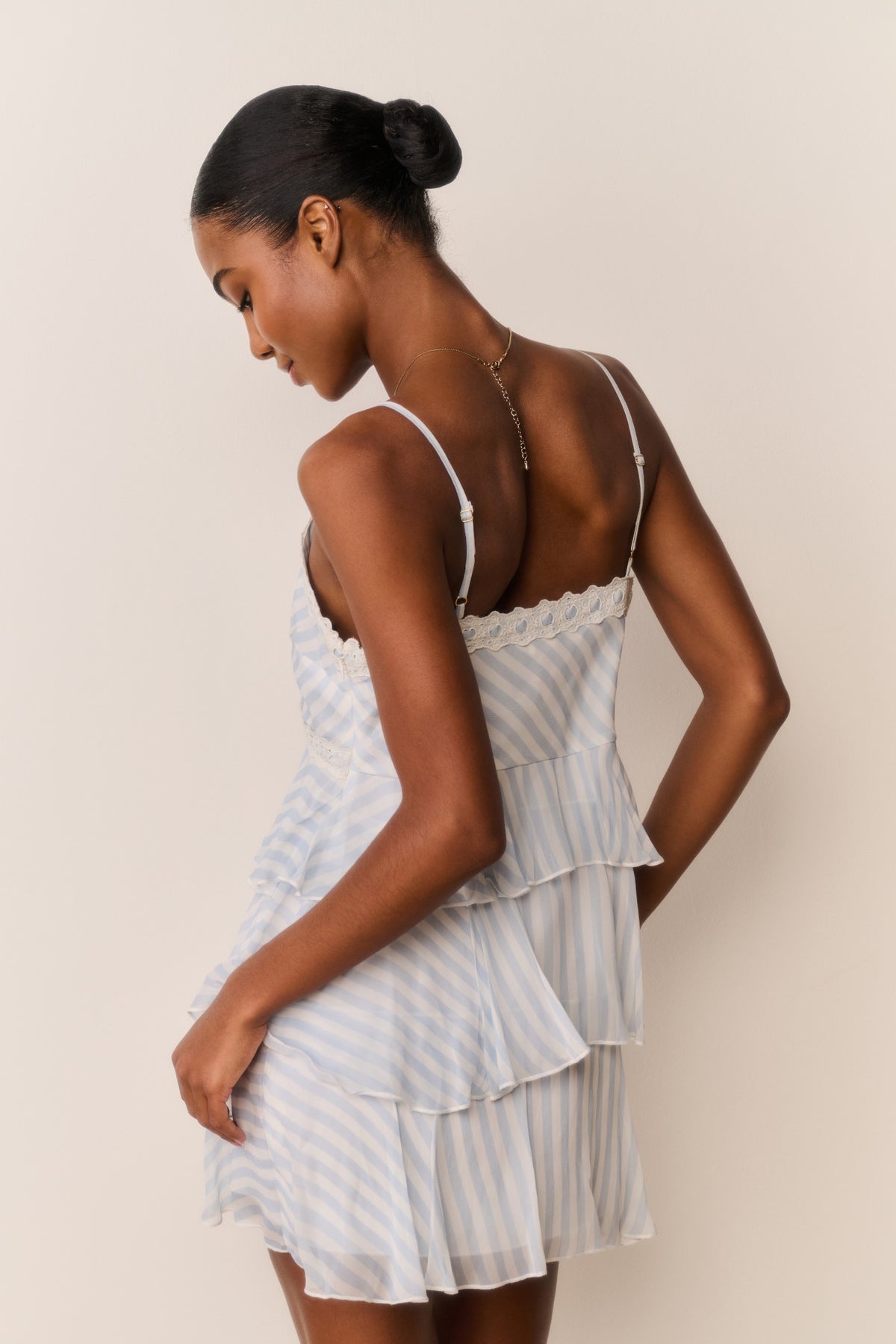 Light blue striped mini dress, open-back style with lace-edged straps and layered ruffles
