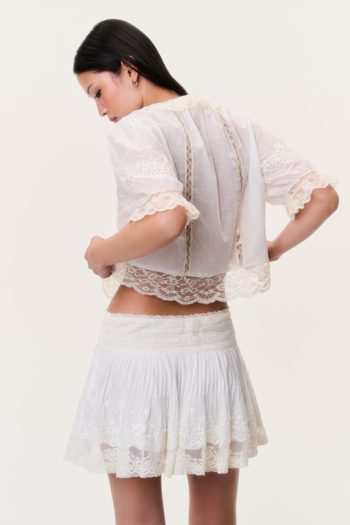 Back view of ivory mini skirt with lace hem and tiered ruffle layers