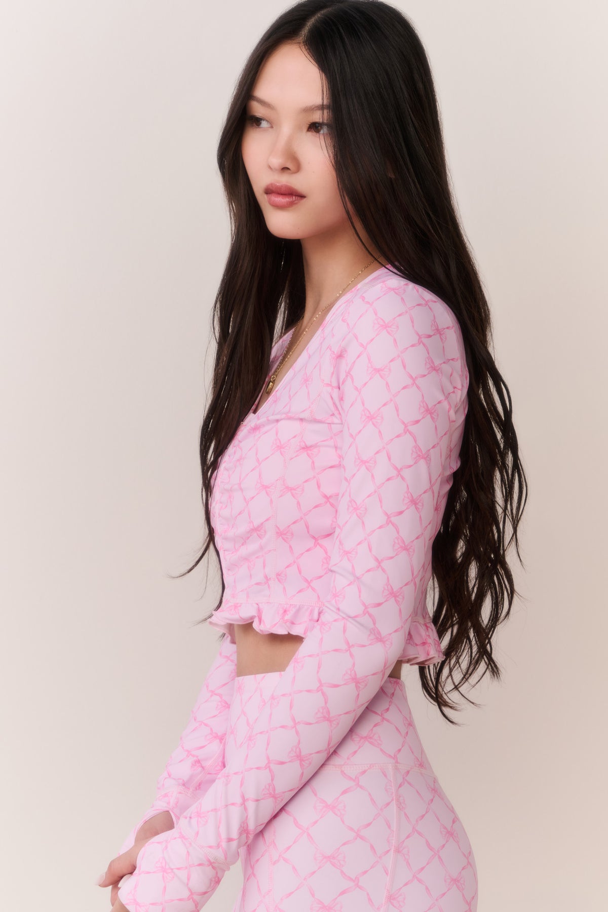 Pink printed zip-up active top with long sleeves and ruffle trim, front zipper detail
