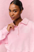 Pink fleece polo sweatshirt with stand collar, button front, and embroidered chest logo