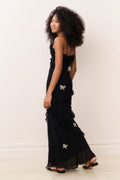 Black sleeveless mini dress with tiered ruffle skirt and bow appliques