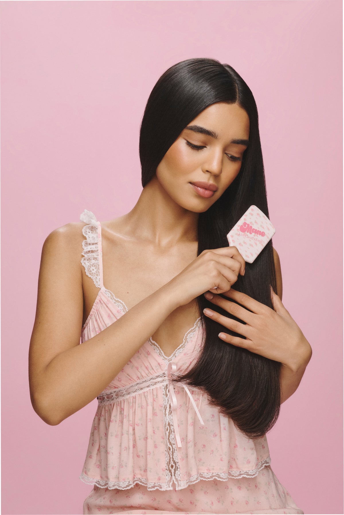 Pink floral mini detangling hair brush held in hand, white handle