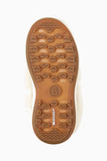 Bottom view of off-white girls boots showing brown traction tread and brand stamp