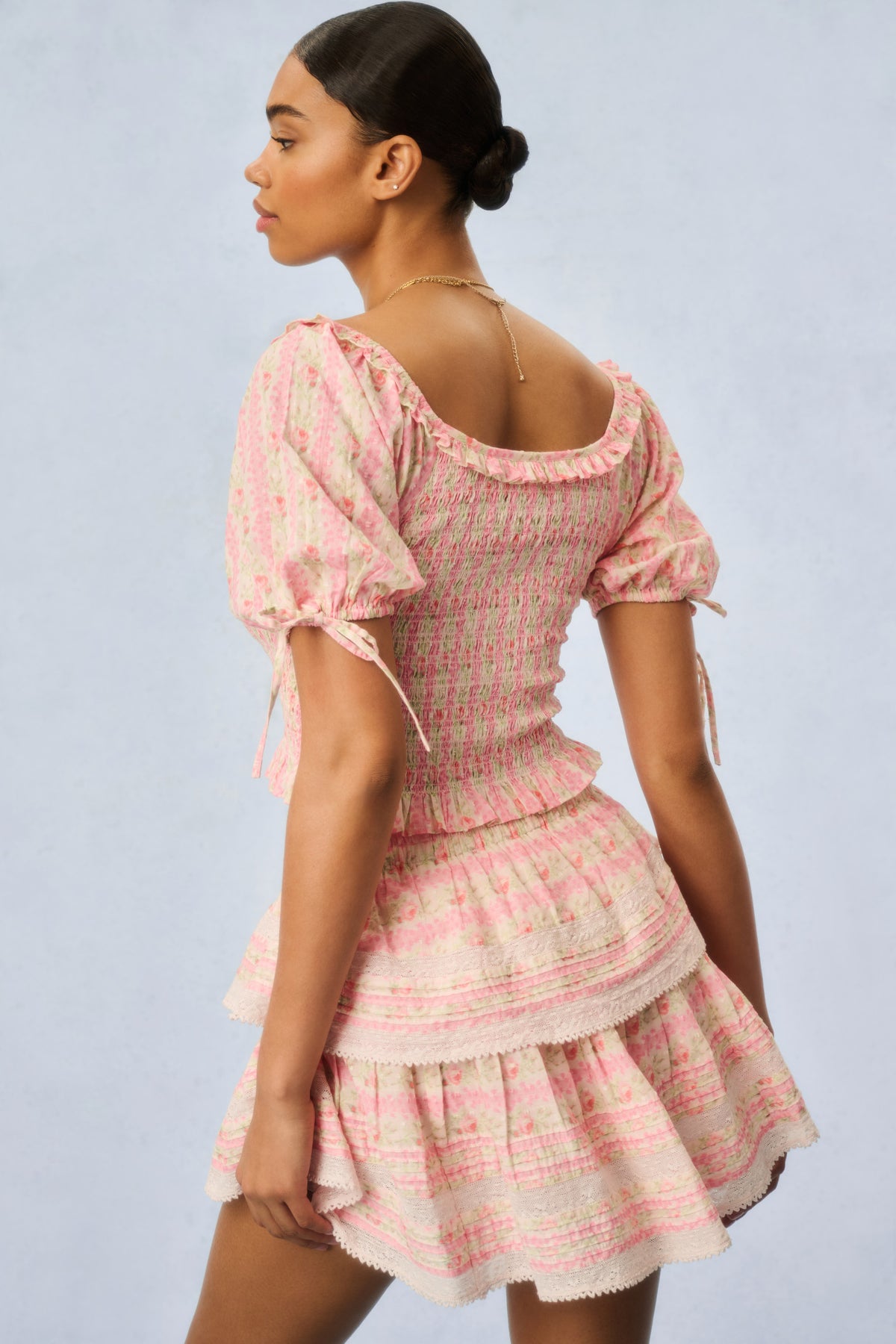 Pink floral print mini dress with tiered ruffles, back view from side