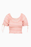 Pink printed peplum top with smocked bodice, puff sleeves, and side tie details