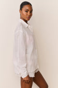 White embroidered cotton button-up shirt on model, long sleeves, scalloped hem finish