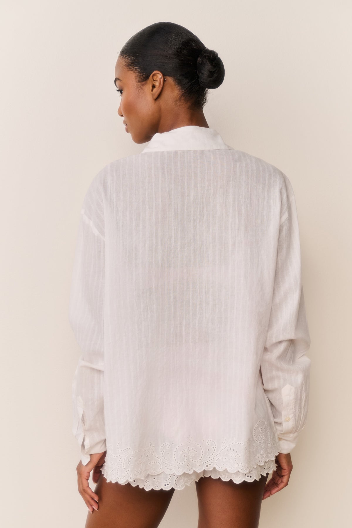 Embroidered cotton button-up shirt from back view, long sleeves, white with scalloped hem