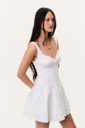 White linen mini dress with V neckline and flared skirt, side view on model