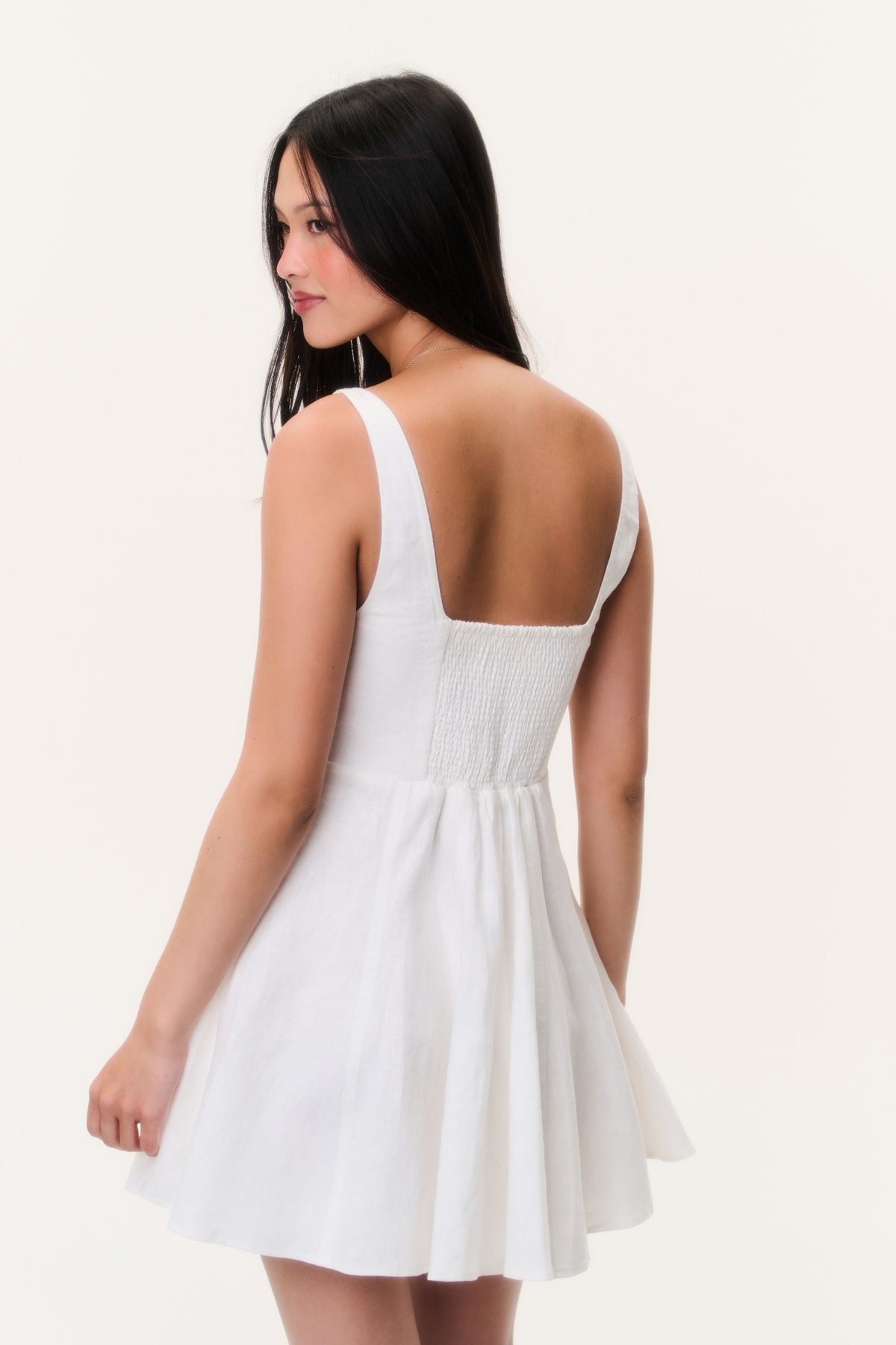 White linen mini dress back view with adjustable straps and gathered waist