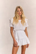 White mini dress with ruffled sleeves, tiered skirt, and vertical embroidered stripes