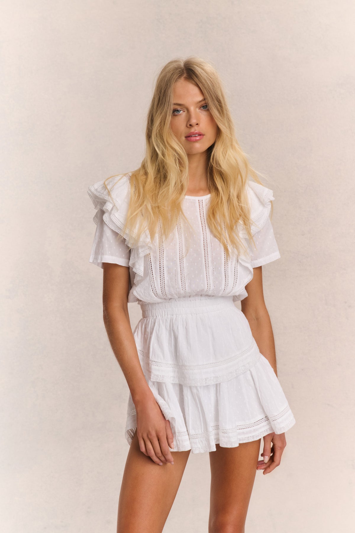 White mini dress with ruffled sleeves, tiered skirt, and vertical embroidered stripes