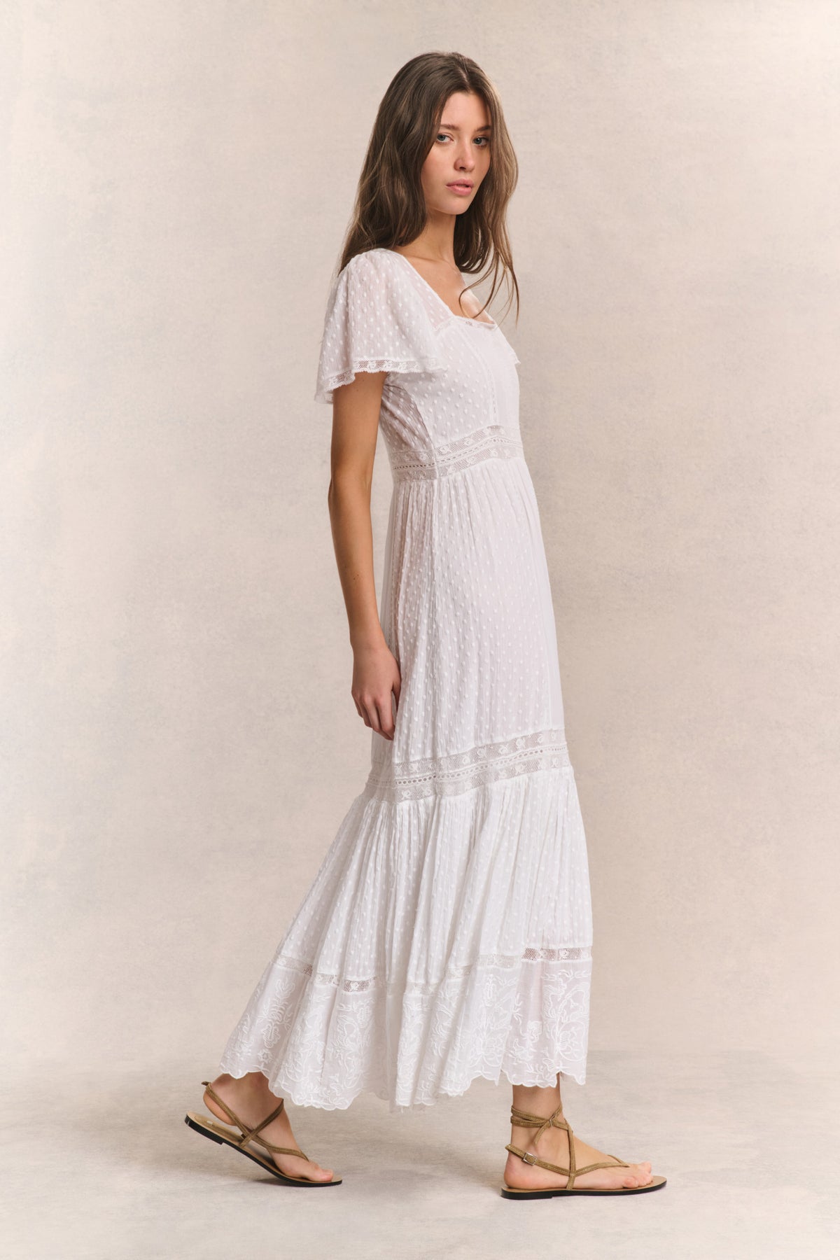 White tiered maxi dress with square neck, lace panel details, and short puff sleeves