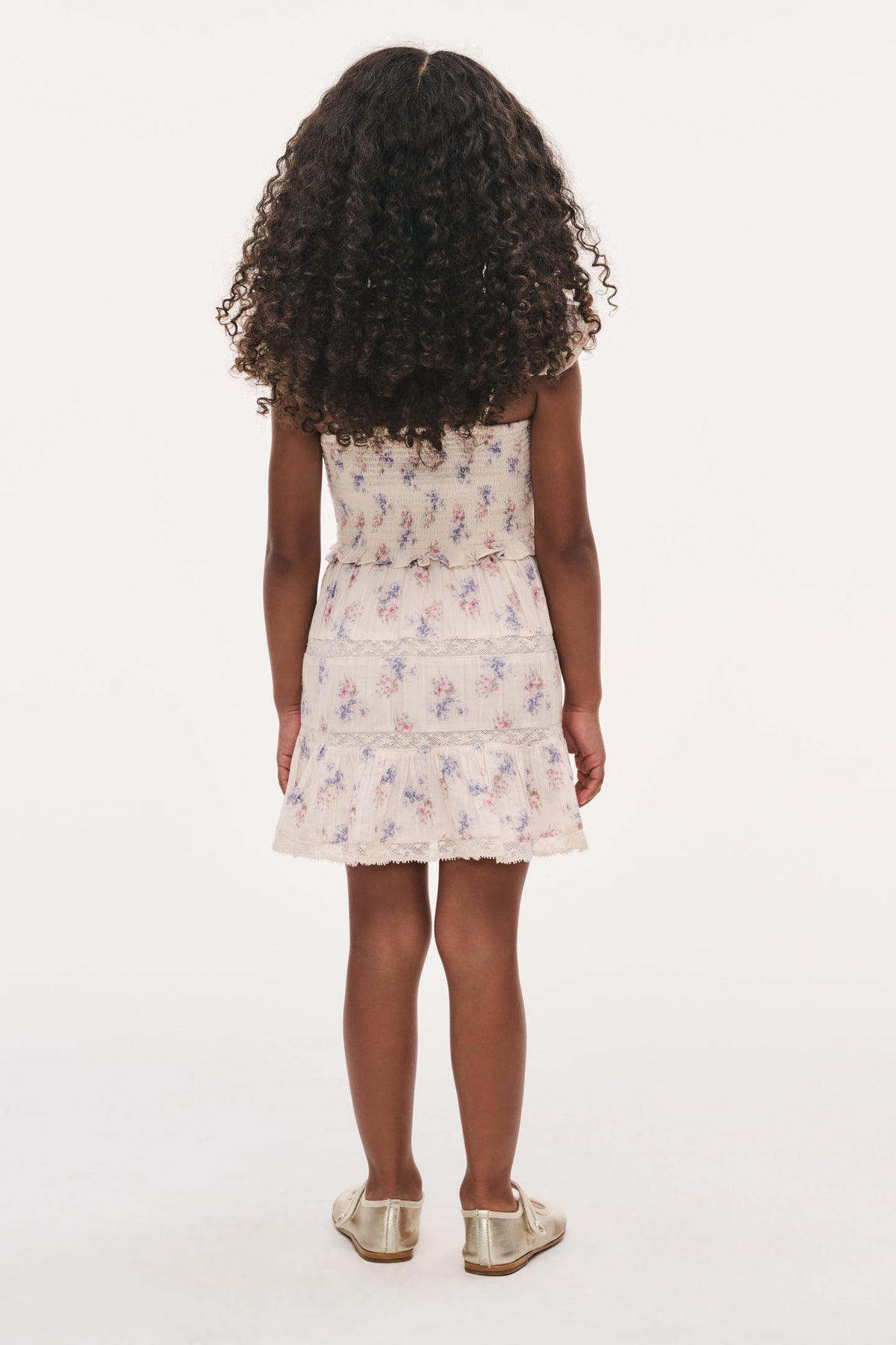 Back view of girls nune dress in antique vanilla, gathered bodice and tiered ruffle skirt.