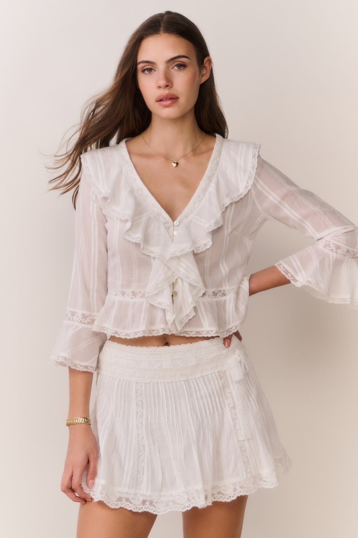 White pleated mini skirt with lace trim and layered ruffle hem, front view