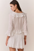 White mini skirt with pleated front, lace trim, and tiered ruffle hem