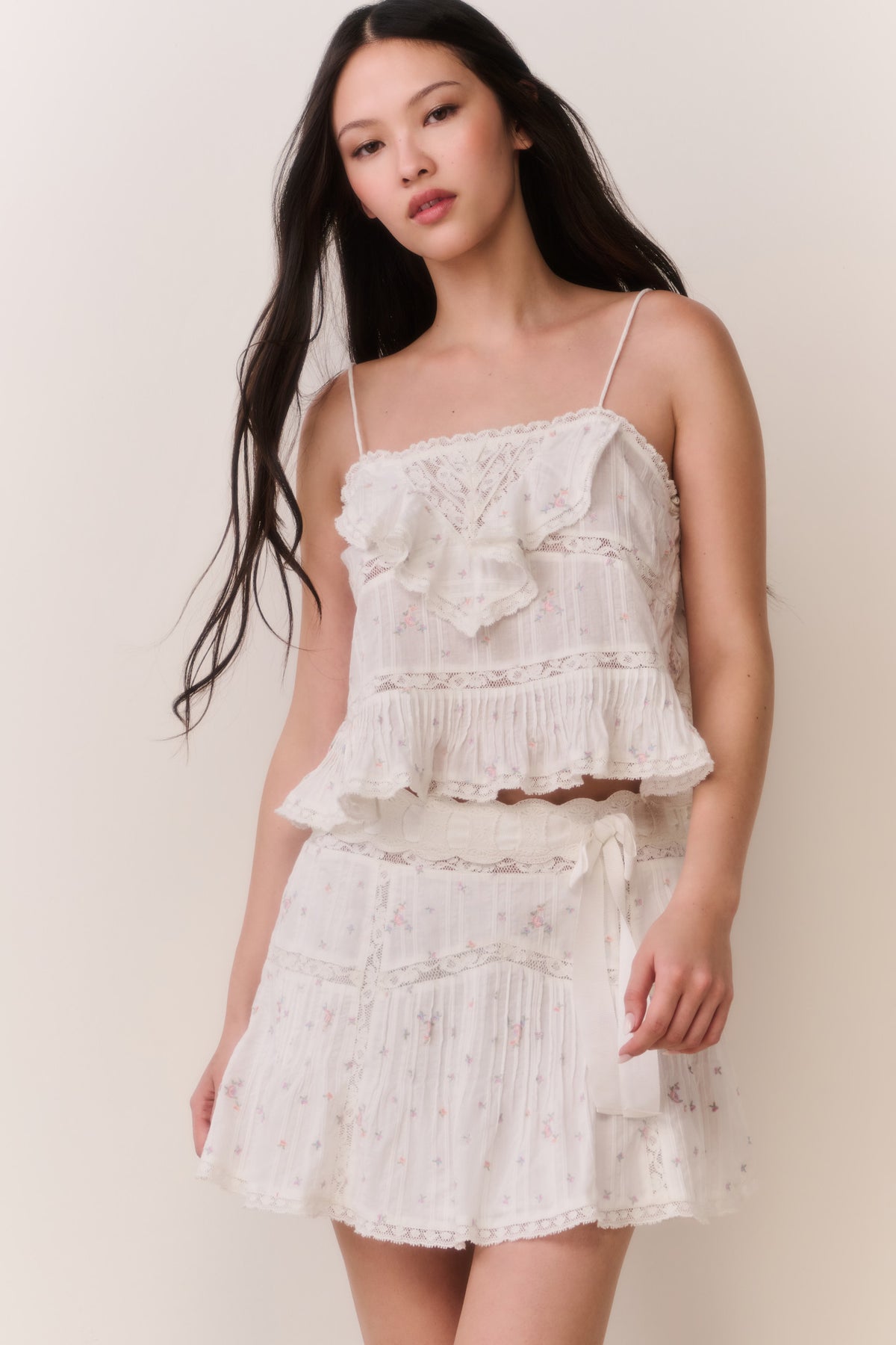 Floral embroidered cotton mini skirt with tiered ruffles and gathered waist (front, angled).