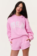 Pink fleece pullover with crew neckline and "USA" graphic; ribbed cuffs and hem.