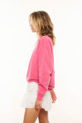 Pink crewneck pullover with long sleeves, side view, ribbed cuffs