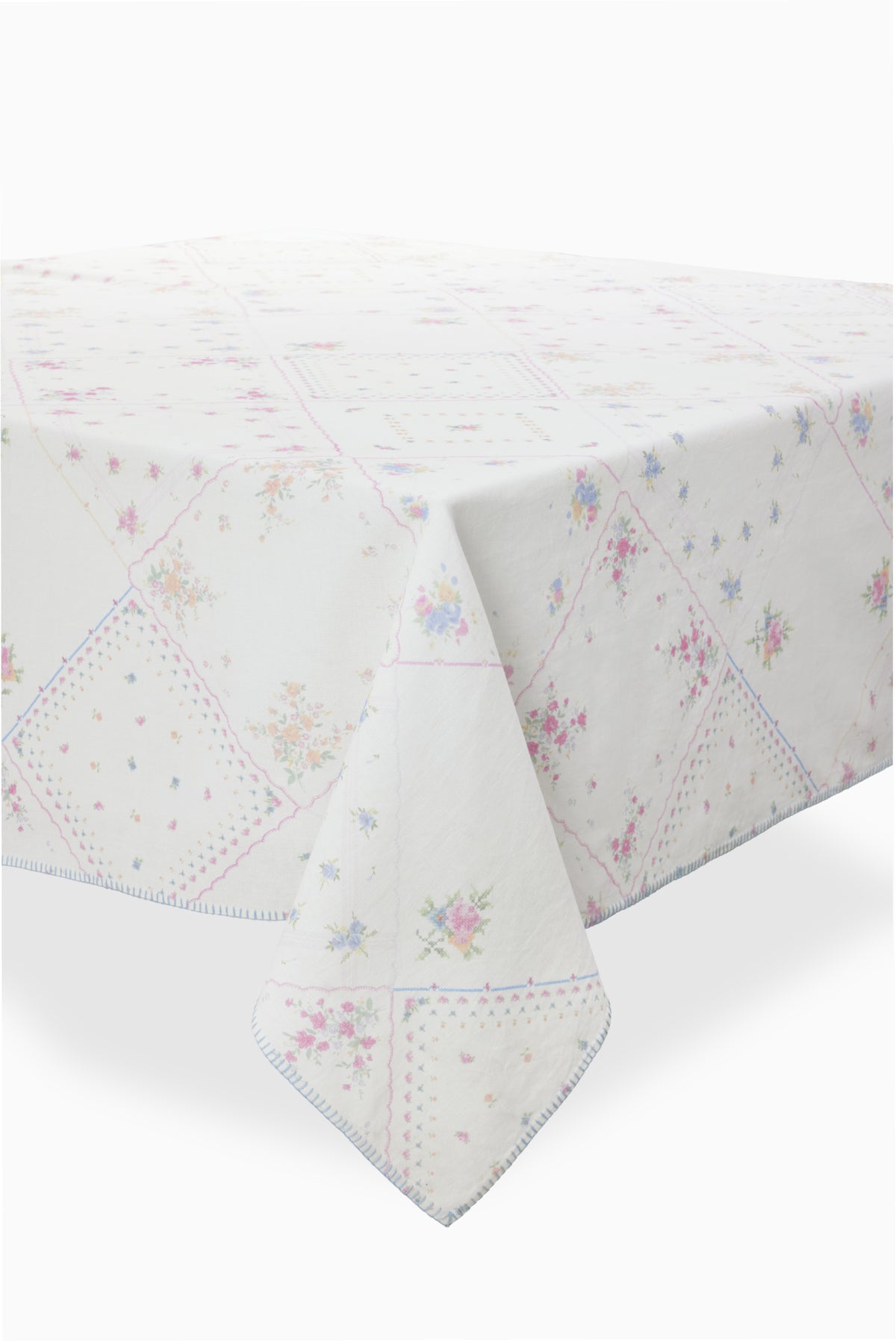 White patchwork table linen with pastel floral diamonds and blue stitched edge trim.