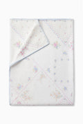 Patchwork table linen, white base with pastel flower motifs and blue stitched border.
