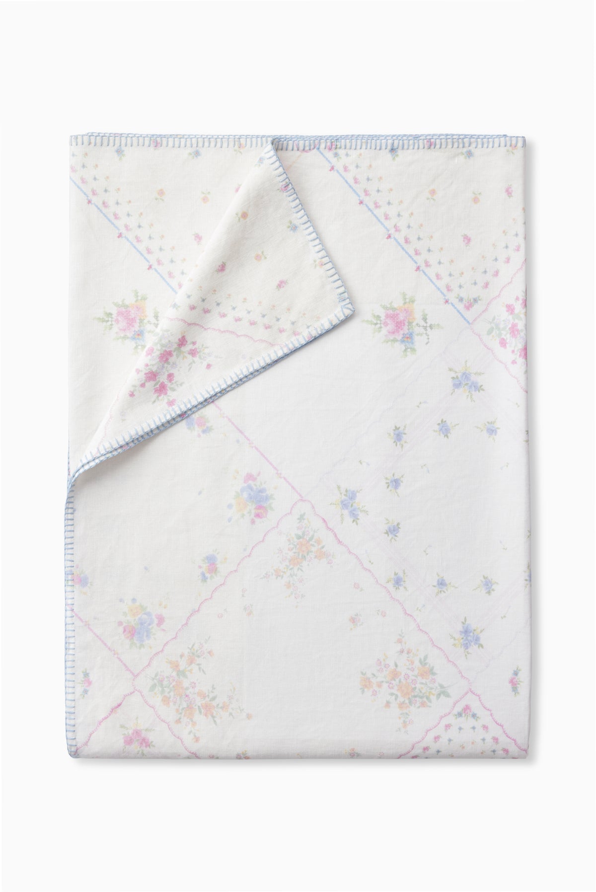 Patchwork table linen, white base with pastel flower motifs and blue stitched border.