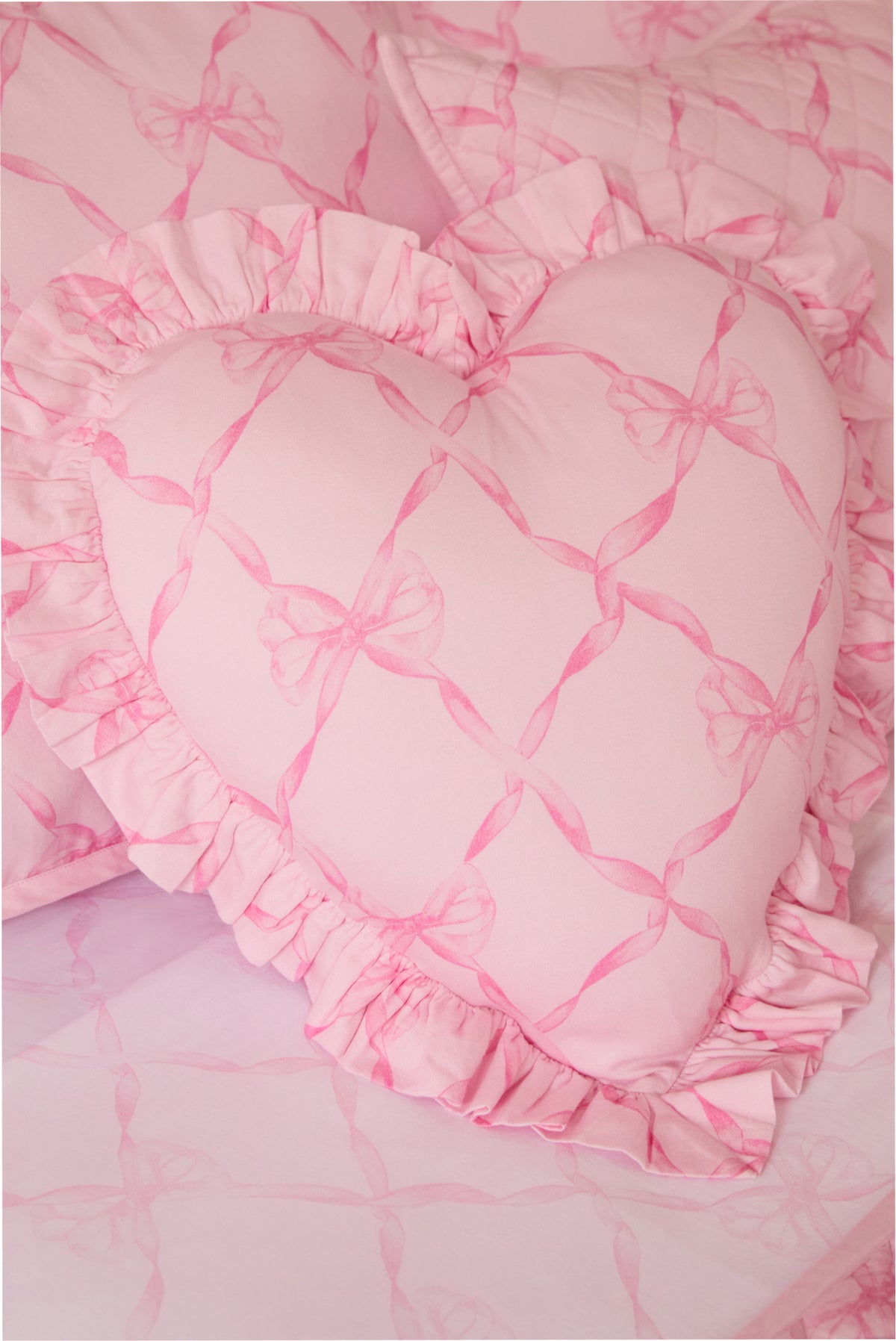 Pink heart pillow close-up with ruffled trim and bow pattern on fabric