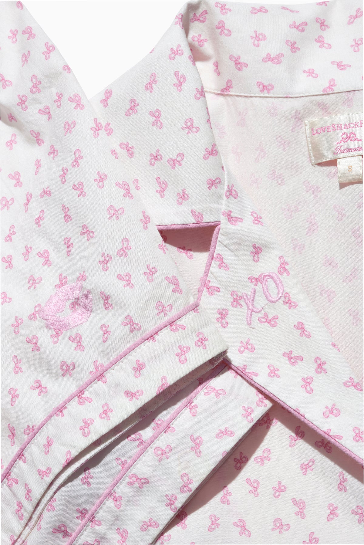 Pink bow-print pajama fabric detail with collar and button placket