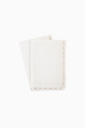 Set of 4 white cloth napkins with scalloped lace borders, stacked